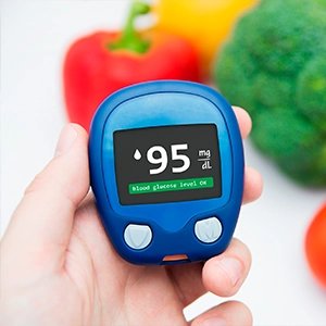 Fresh vegetables arranged beside a glucose monitor, representing balanced nutrition and glucose wellness